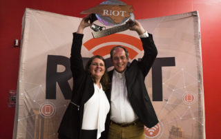 a man and woman accept an award at the RIoT Accellerator Program